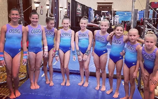 a group of girls in swimsuits standing on a pool