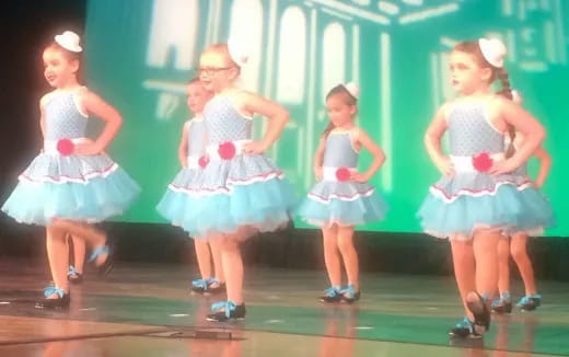 a group of girls in dresses on a stage