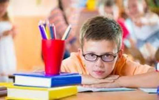 a boy with glasses and his head in his hands