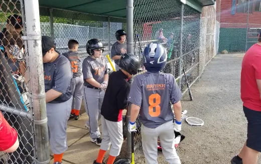 a group of people stand around a baseball field