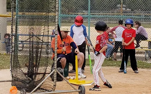 kids playing baseball in a cage