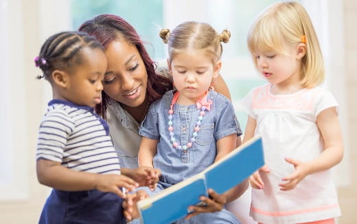 a person and several children looking at a book