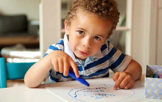 a young boy coloring on a paper
