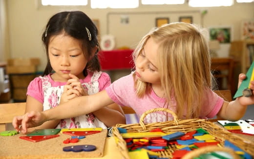 a couple of young girls playing with toys on a table