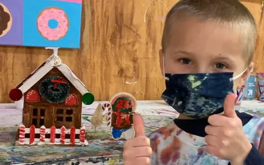 a baby sitting at a table with a toy house