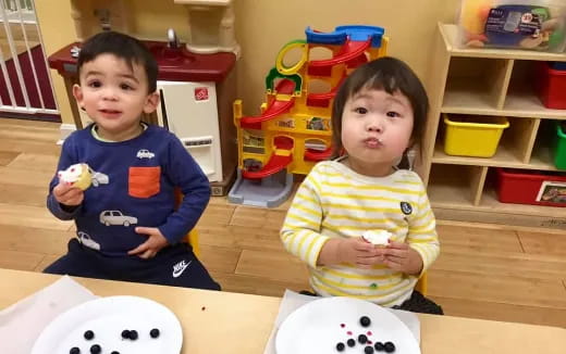 a couple of kids sitting at a table with a toy