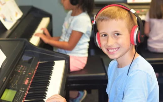 a boy wearing headphones and playing a piano