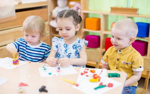 a group of children sitting at a table with a cake