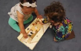 a couple of girls playing with a puzzle