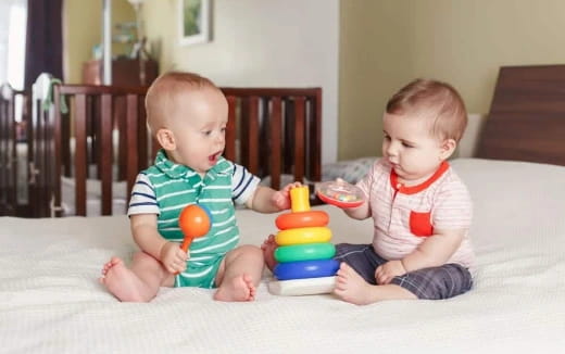 two babies sitting on a bed