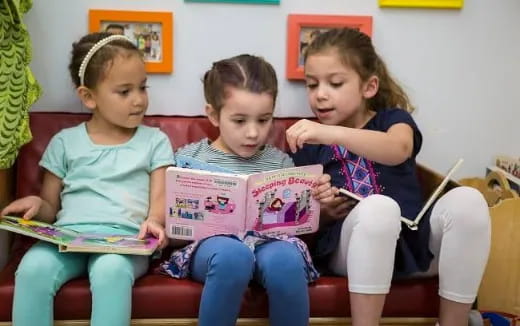 a group of children sitting on a couch reading books