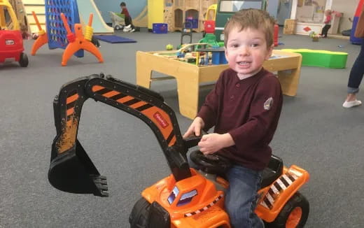a boy sitting on a toy tractor