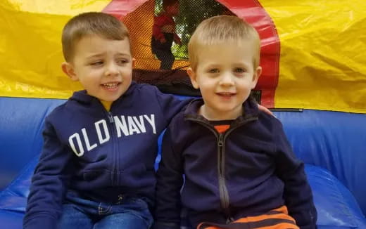 two boys sitting on a blue blanket