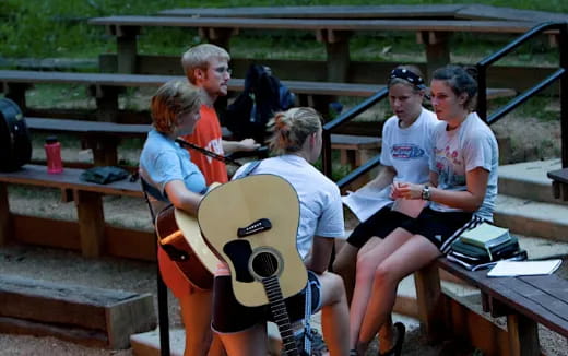a group of people sitting on a bench with a guitar