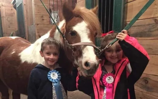 a couple of people stand near a horse