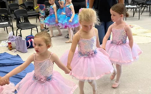 a group of girls in dresses dancing