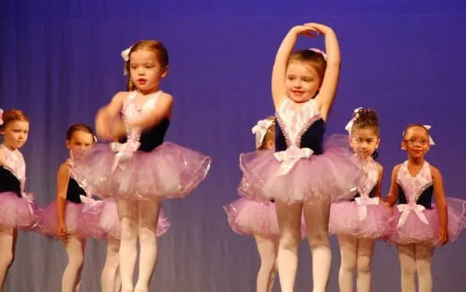 a group of girls in dresses on a stage