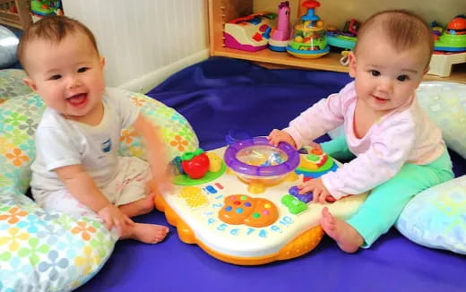 two babies sitting on a blanket