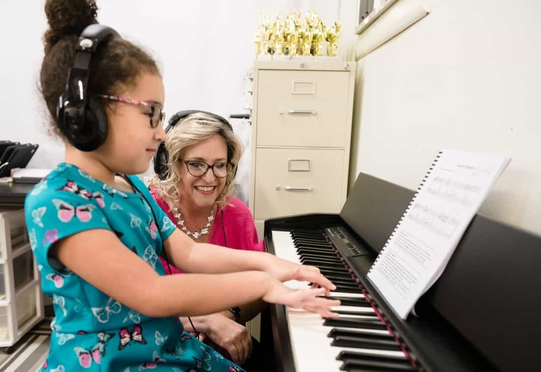 a person playing a piano with a person sitting next to the