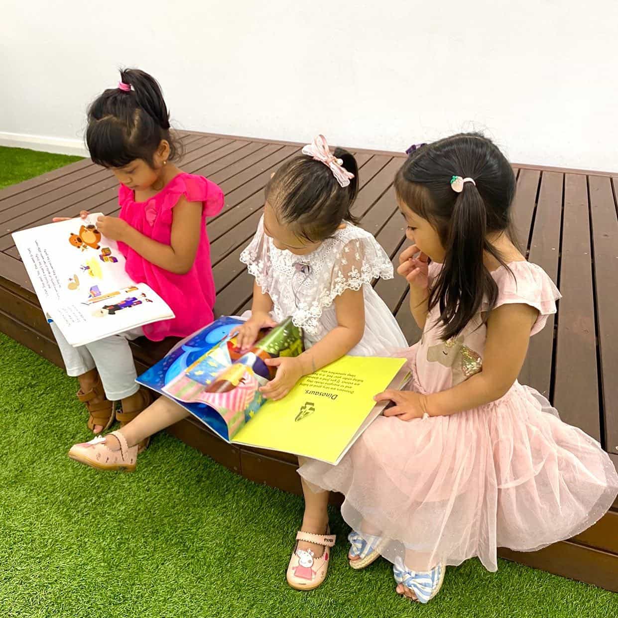 a group of girls sitting on a bench reading a book