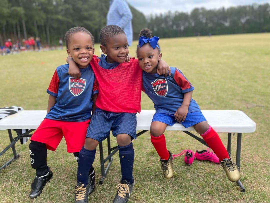a group of boys sitting on a bench in a field