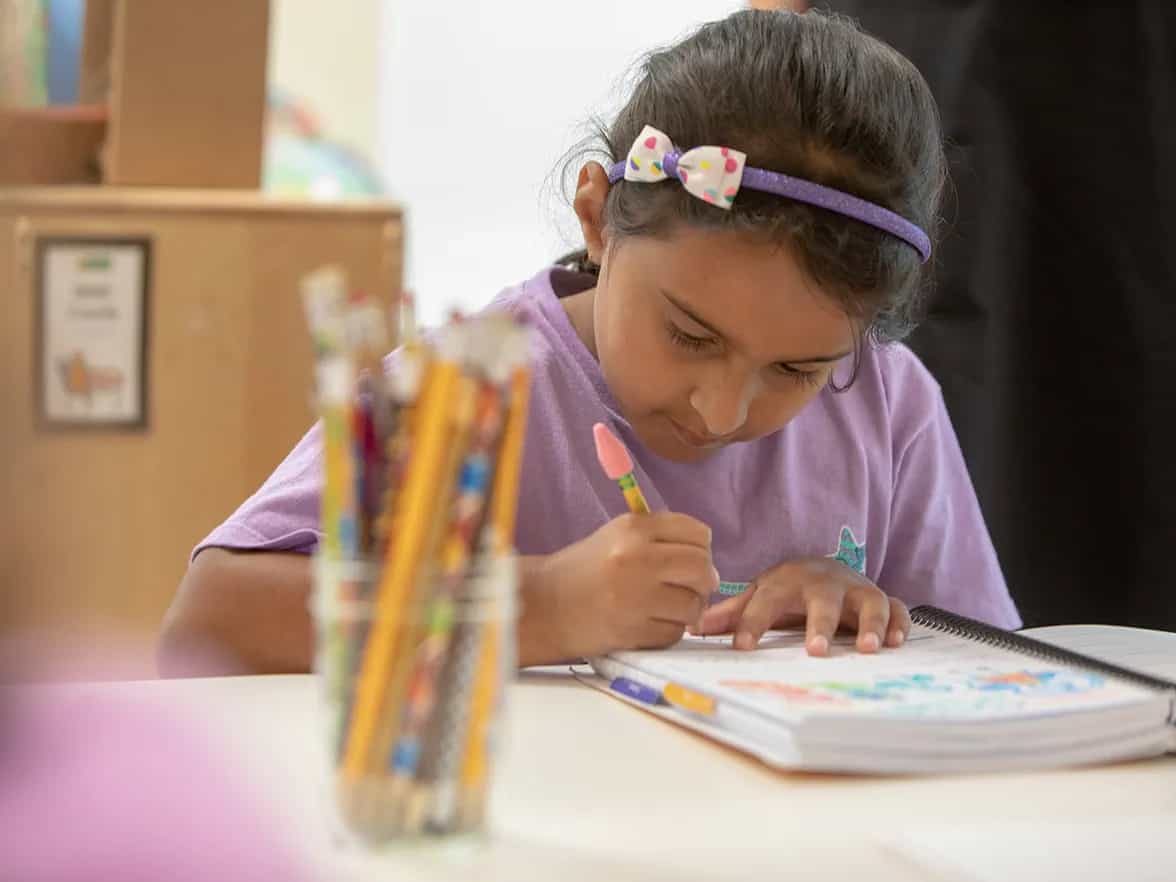 a young girl writing on a piece of paper